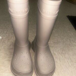 Balenciaga x Crocs rubber boots in a beige or taupe color.